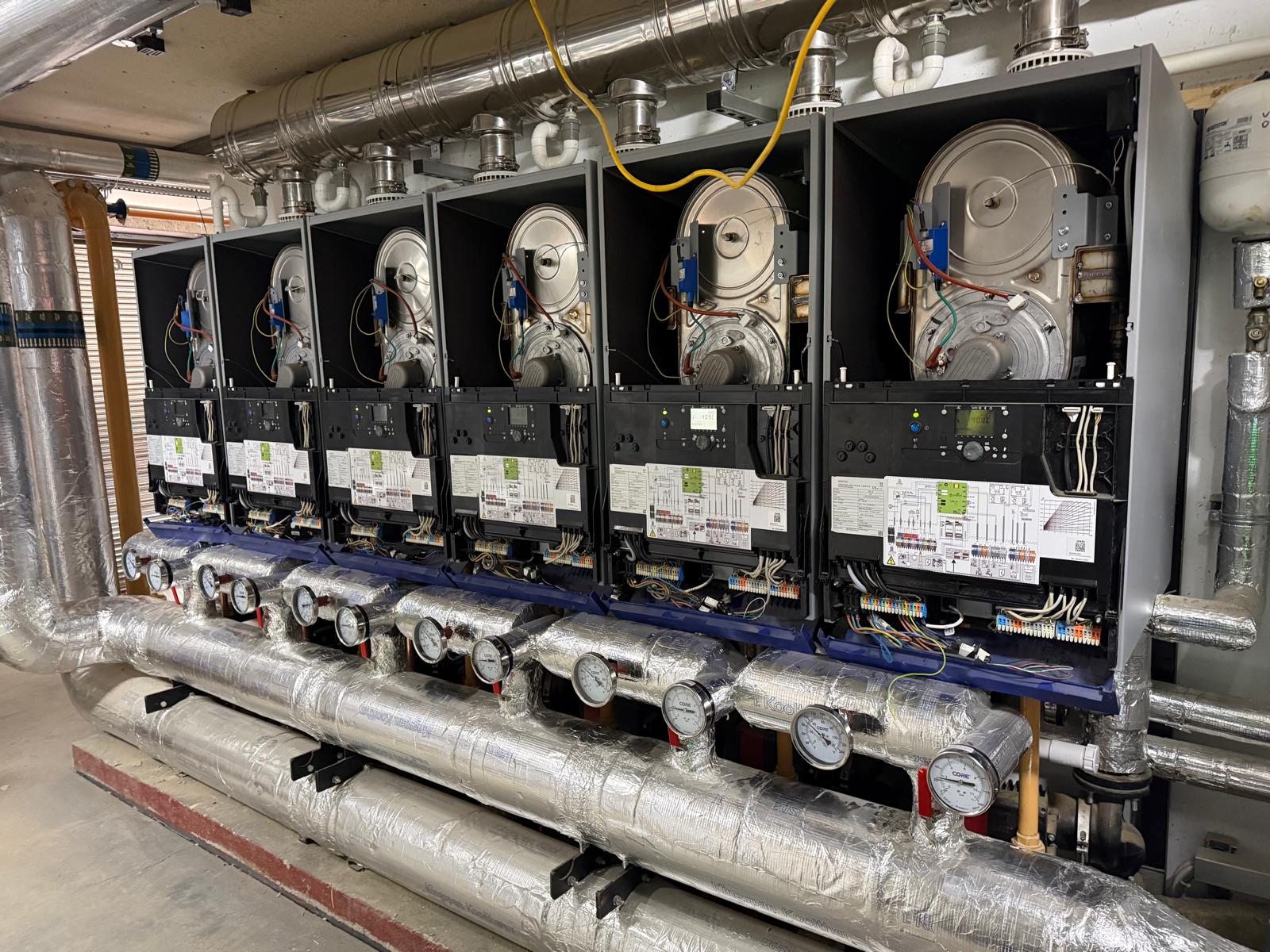 Six Hamworthy Stratton boilers with control panels lifted, wired back to the BMS on a new LTHW installation